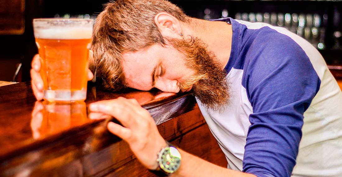 a man with a beer mug is sleeping at the bar